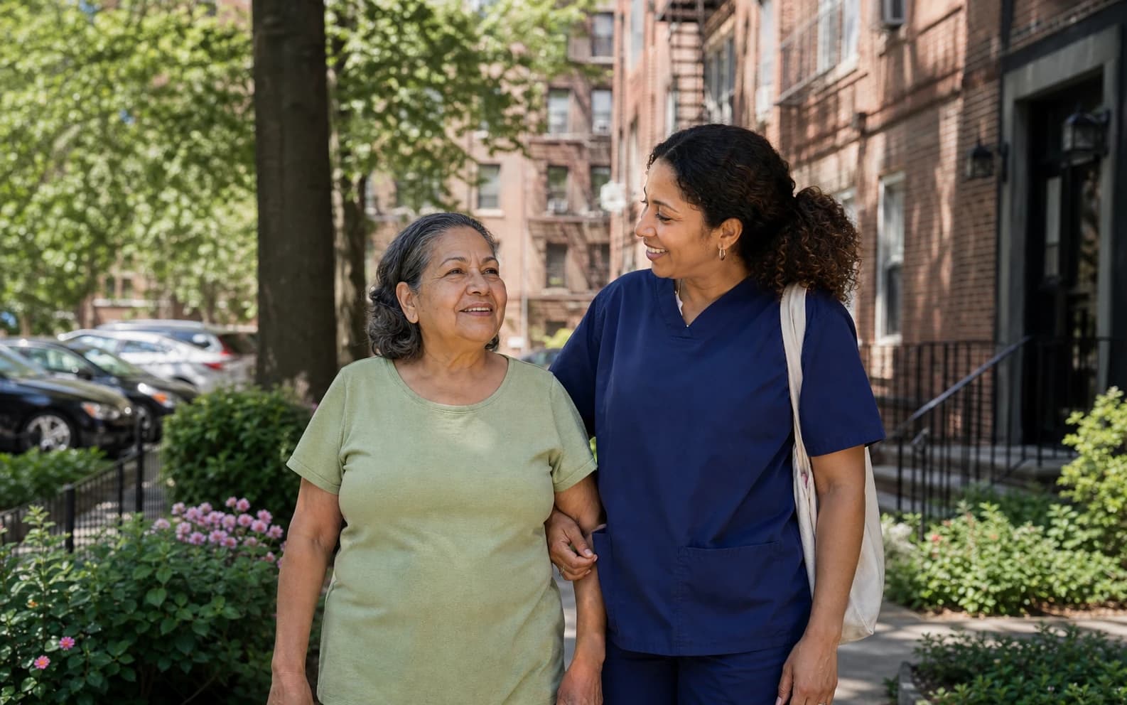 A senior caregiver walking with an older woman outside her home in Queens County